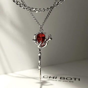 Red gemstone pendant necklace with silver chain on a black background