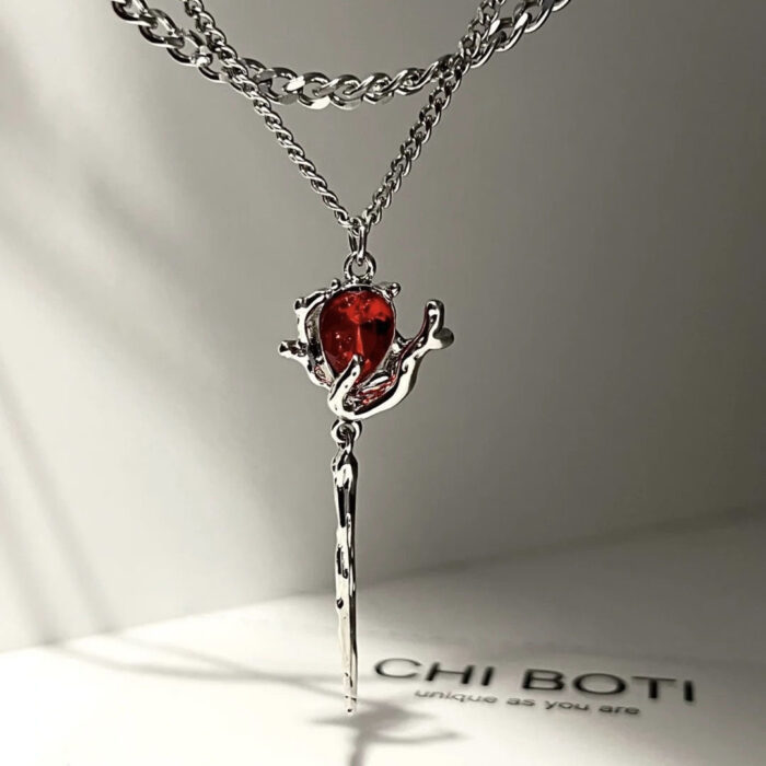Red gemstone pendant necklace with silver chain on a black background